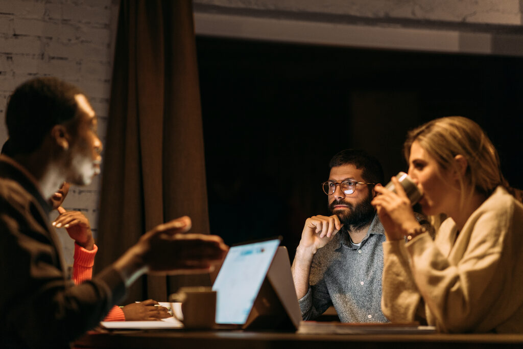 A team discussing work around a laptop in a dim evening office