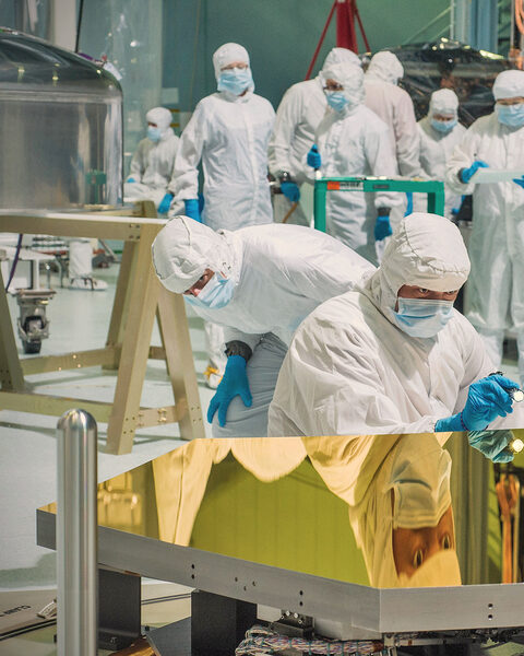 Engineers in clean-room suits inspecting the James Webb Space Telescope's gold flight mirrors